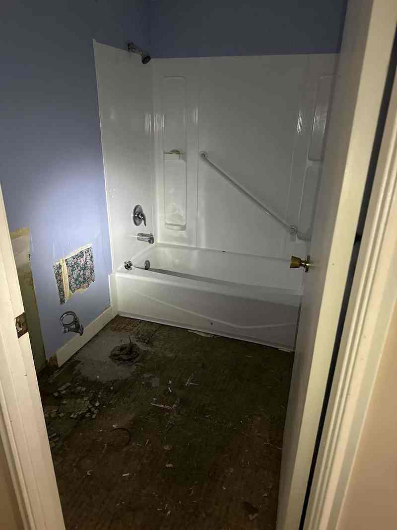 The same bathroom after the work, with a clean white tub and finished walls.