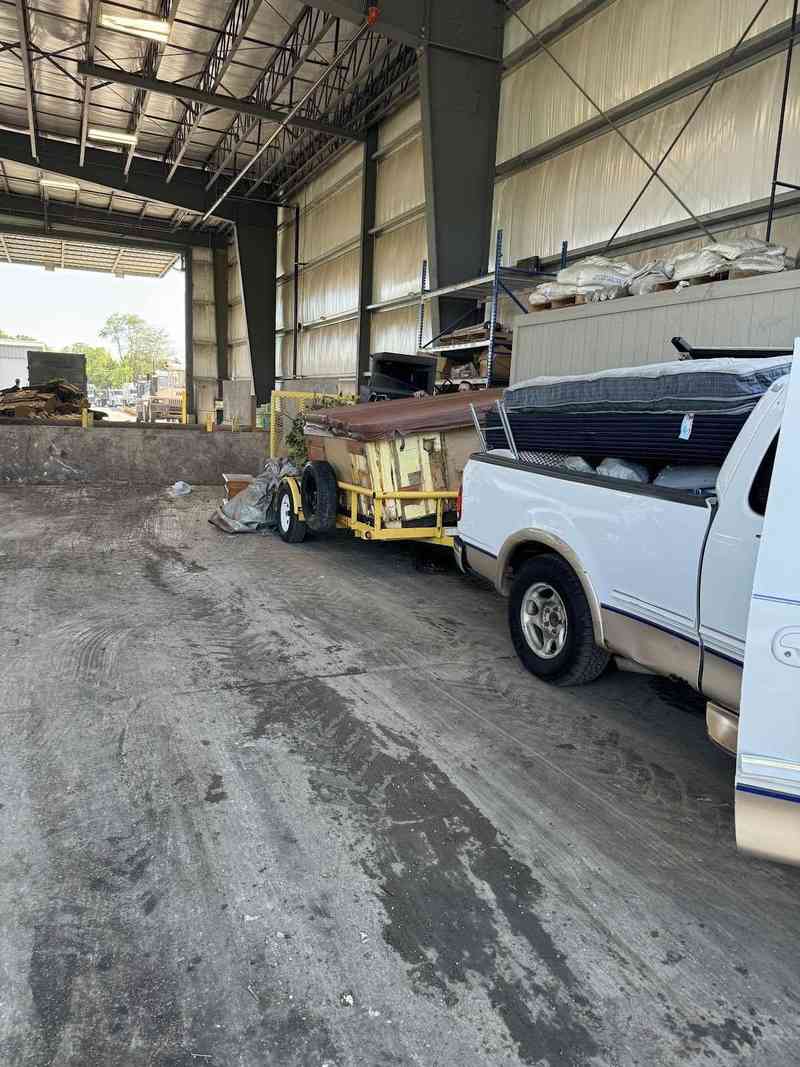 A white work van and trailer inside a covered work area.