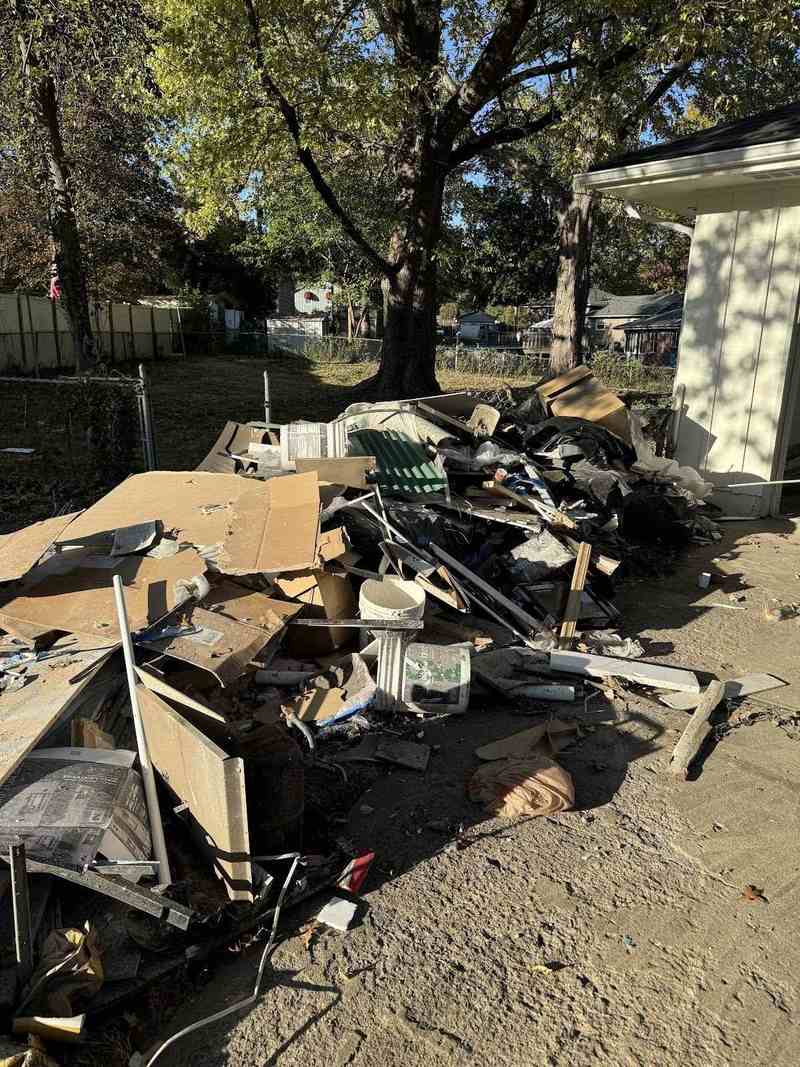A large pile of mixed household and construction debris in a yard.
