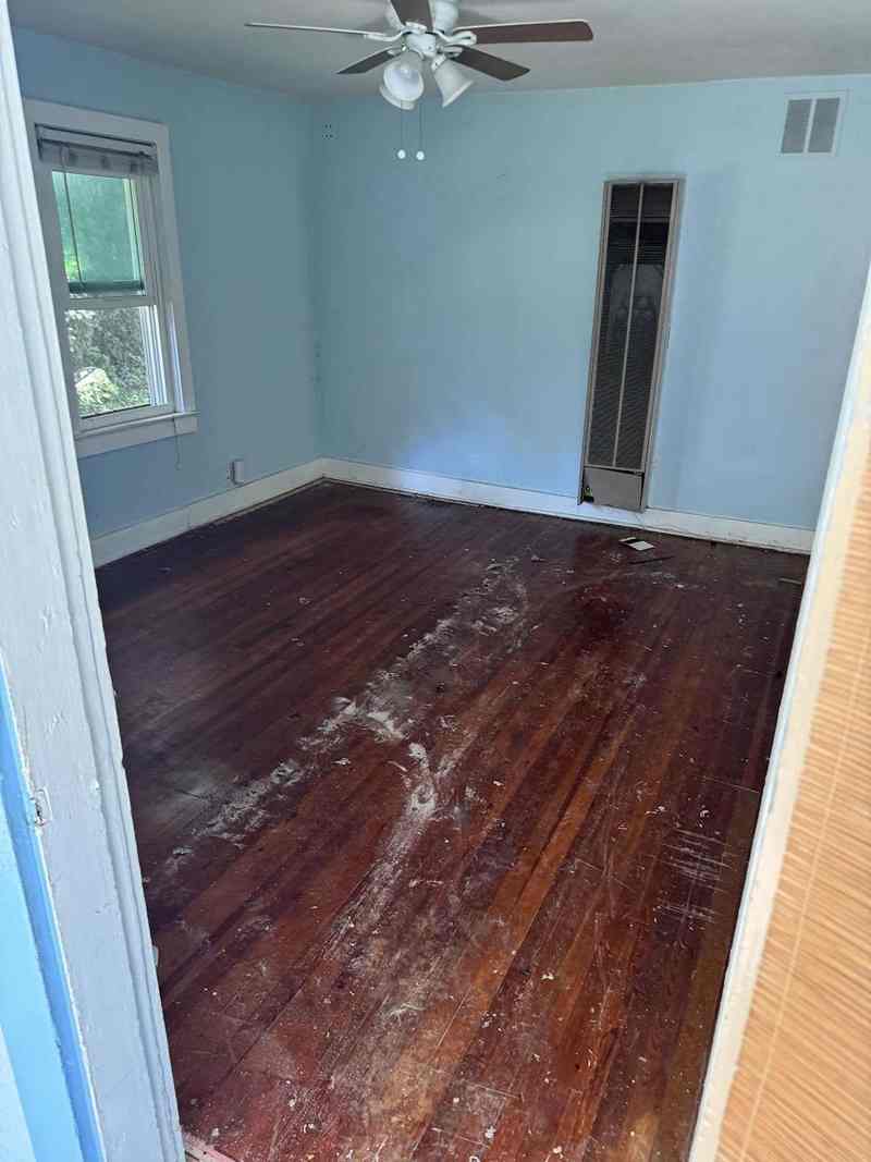 A bright room with cleared hardwood flooring and a blue-painted wall.